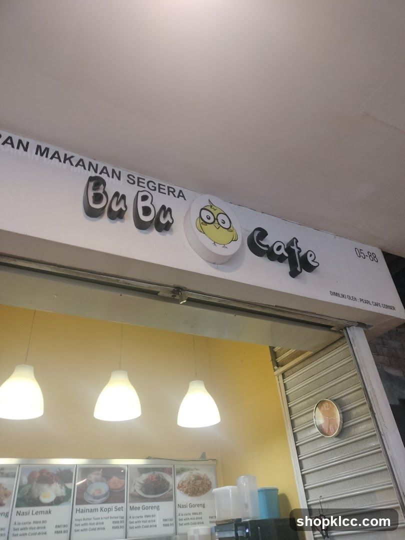 The exterior of a cafe with a prominent sign that reads "BuBu Cafe" and a cartoon owl logo. Below the sign, there are framed pictures of food items with their prices.