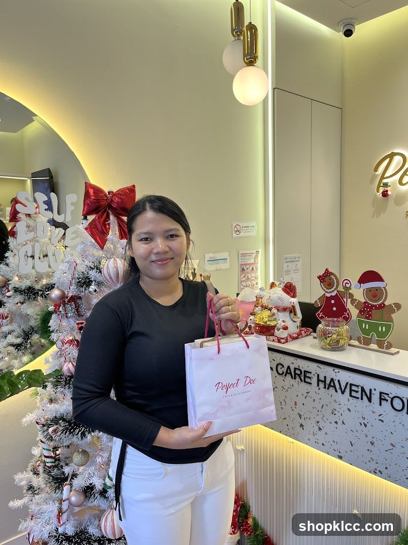 Woman holding a gift bag in front of a Christmas tree
