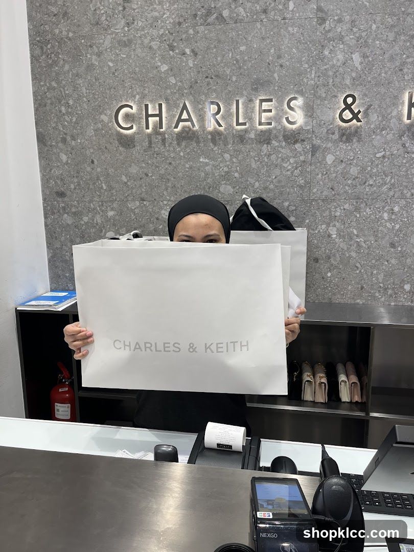 Woman holding shopping bag in front of Charles & Keith store