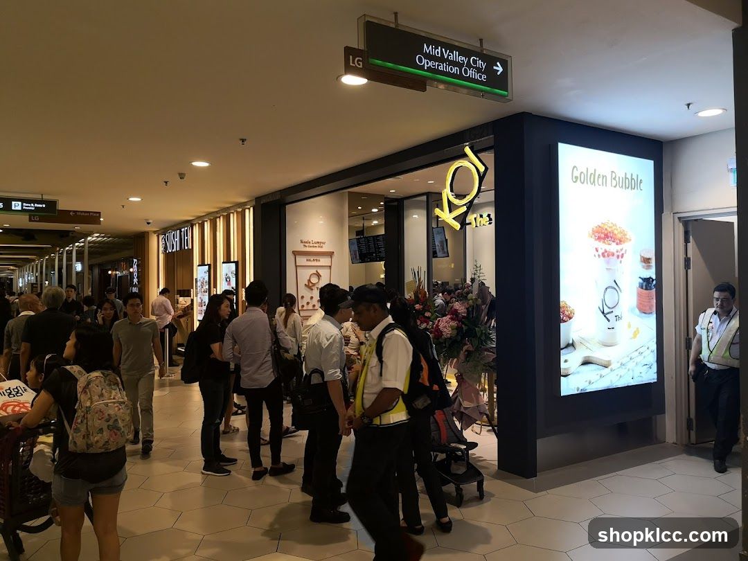 Busy shopping mall corridor with various shops and people