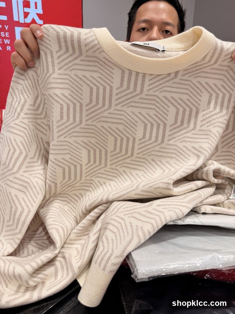 Man holding a cream-colored sweater with a geometric pattern
