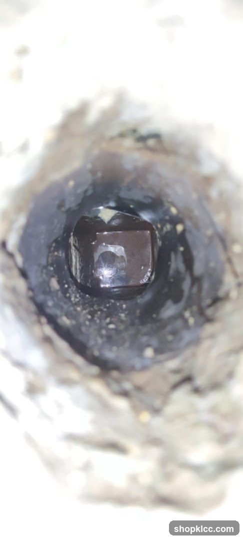 Close-up of a dark, glossy object in a rough texture