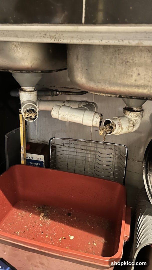 Under-sink area with plumbing and storage bin