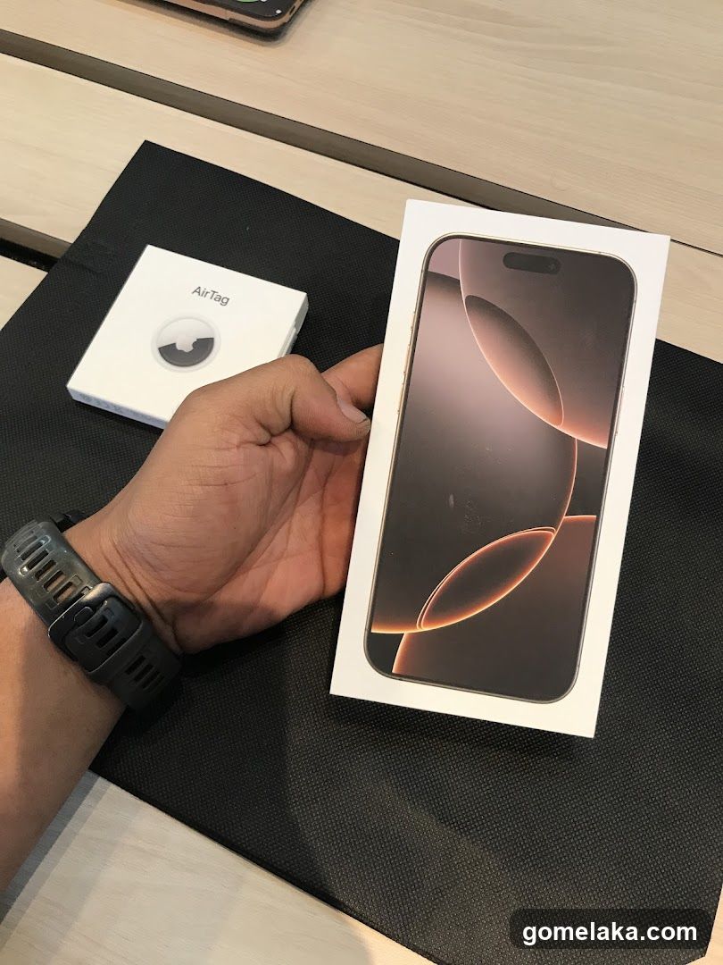 Hand holding iPhone box with AirTag box nearby