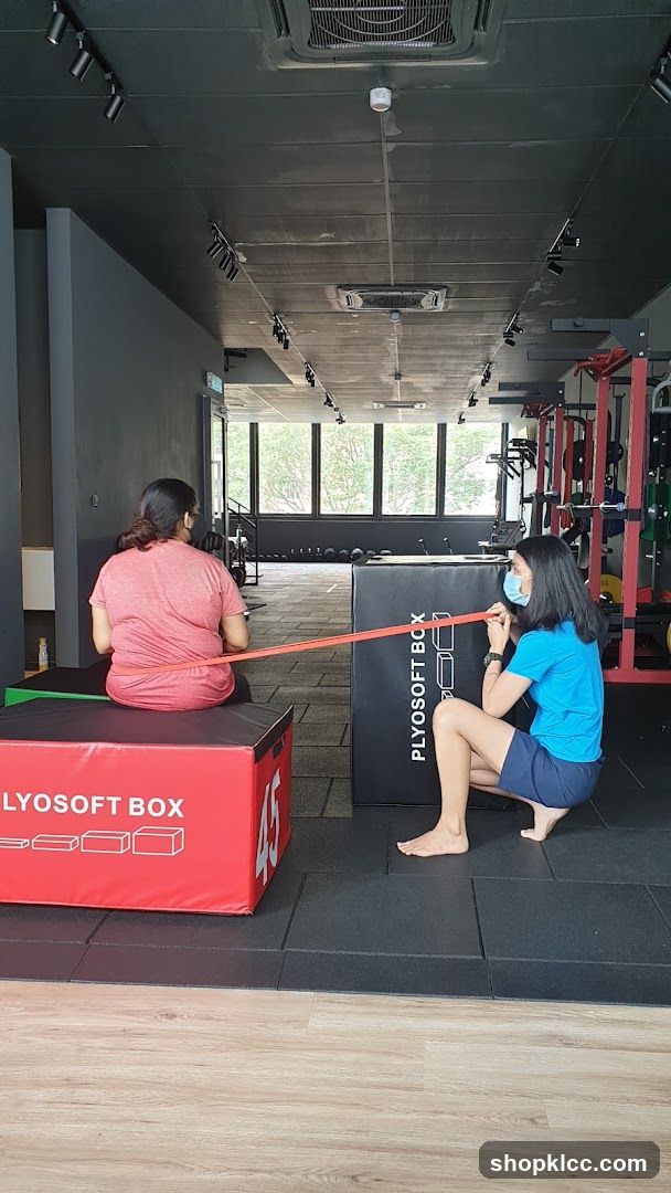 Two people exercising with a resistance band in a gym