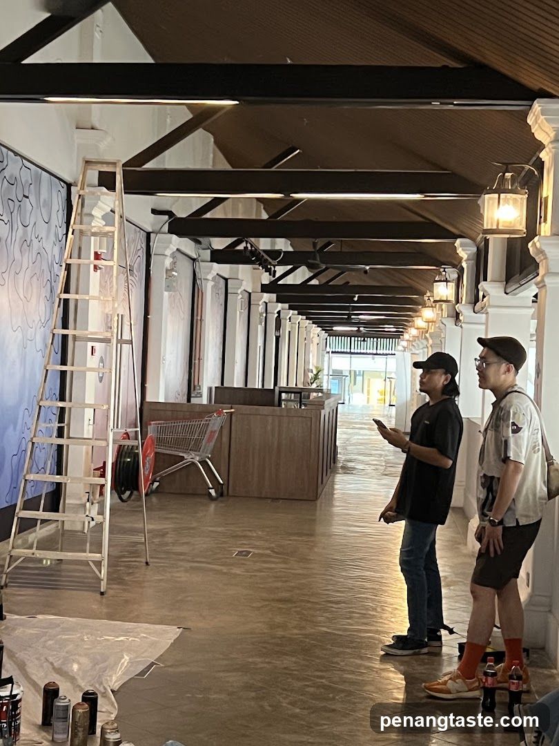 Two men observing a mural in progress