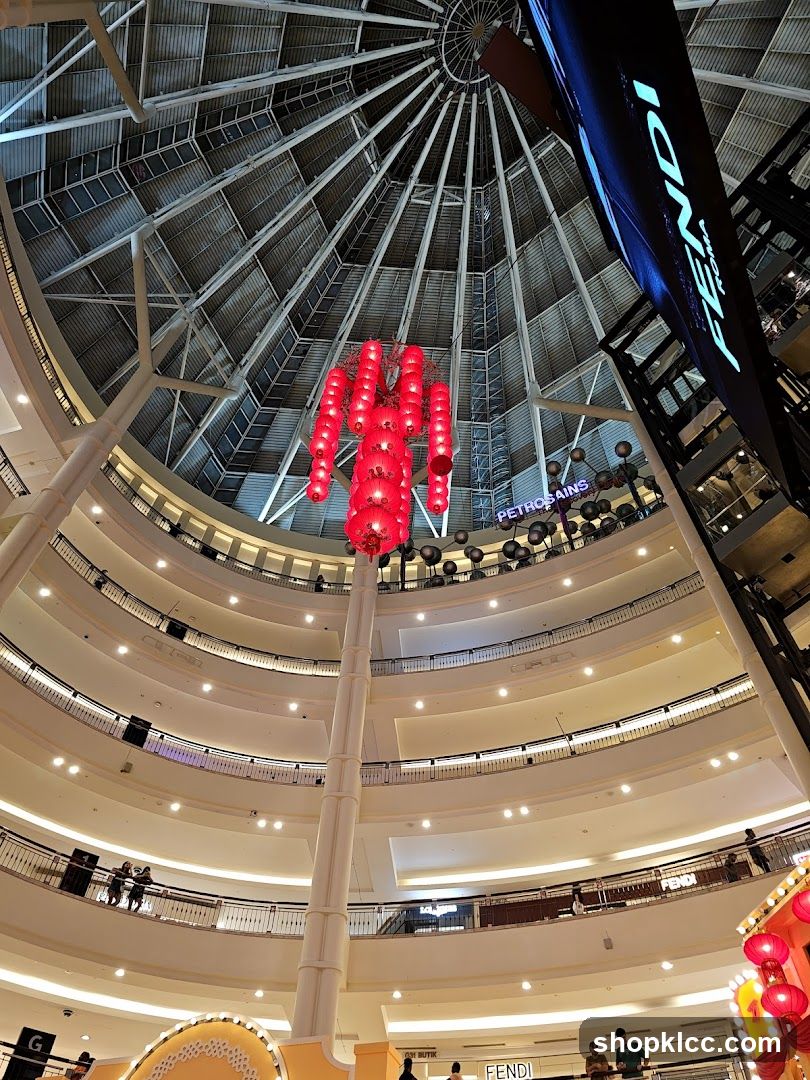Interior of a multi-level shopping mall with a large dome ceiling and red lantern decorations.