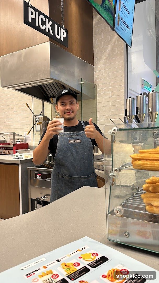Staff member holding a drink and giving a thumbs up