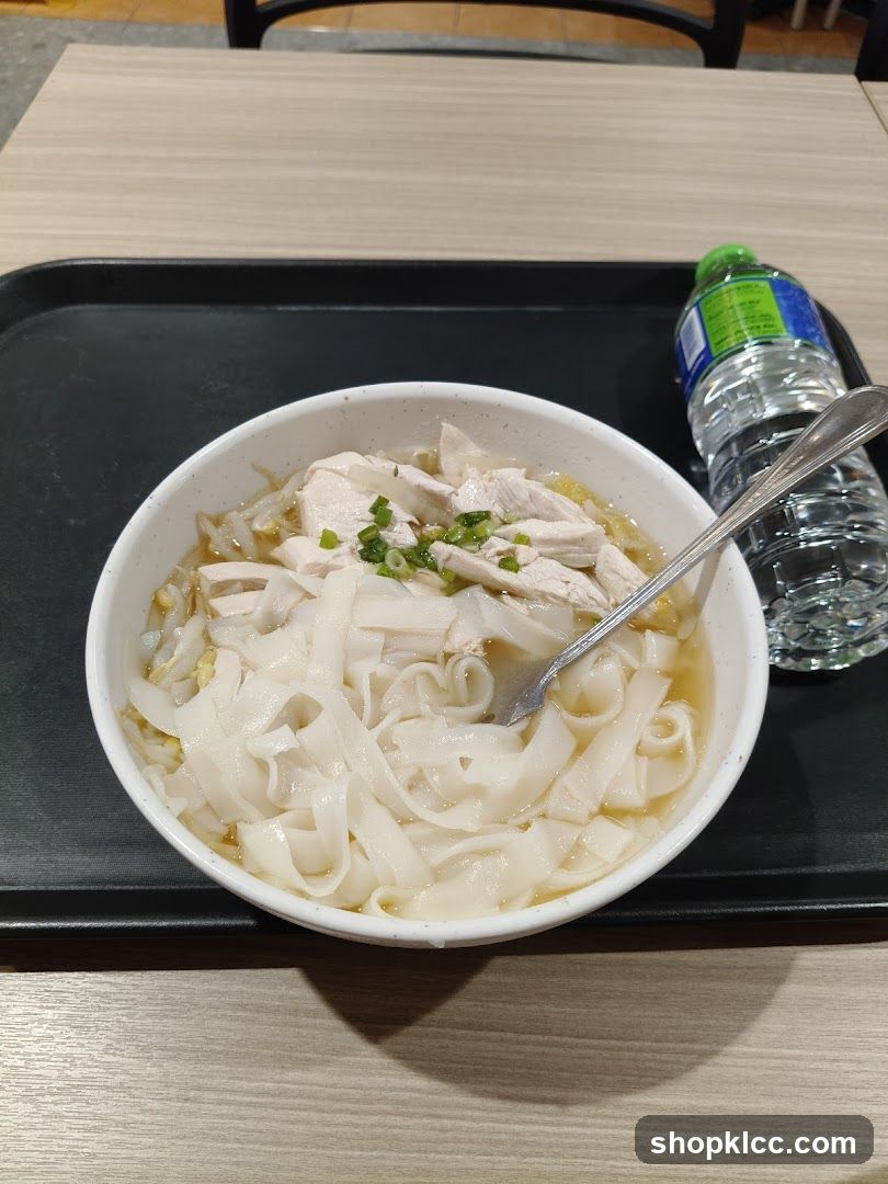 Bowl of noodles with chicken and water bottle on tray