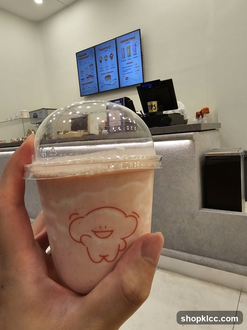 Hand holding a pink smoothie in a store
