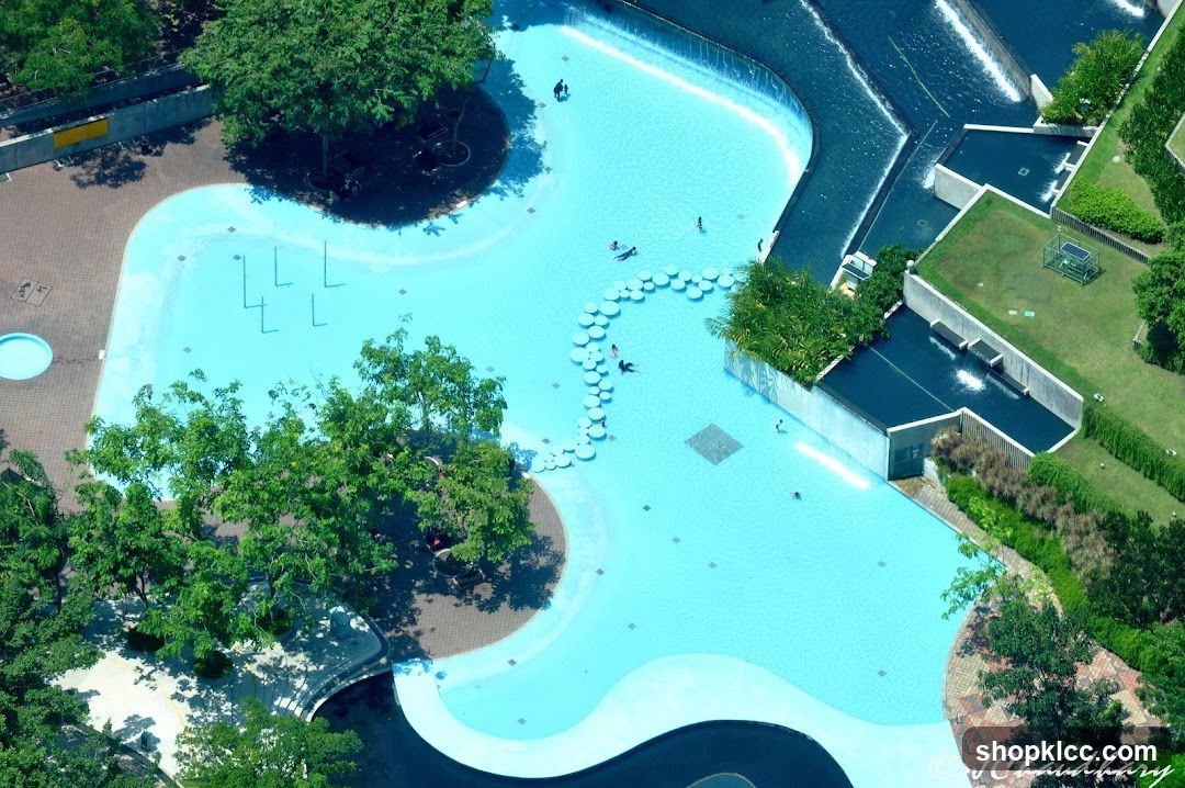 Aerial view of a public swimming pool with surrounding greenery and architecture.