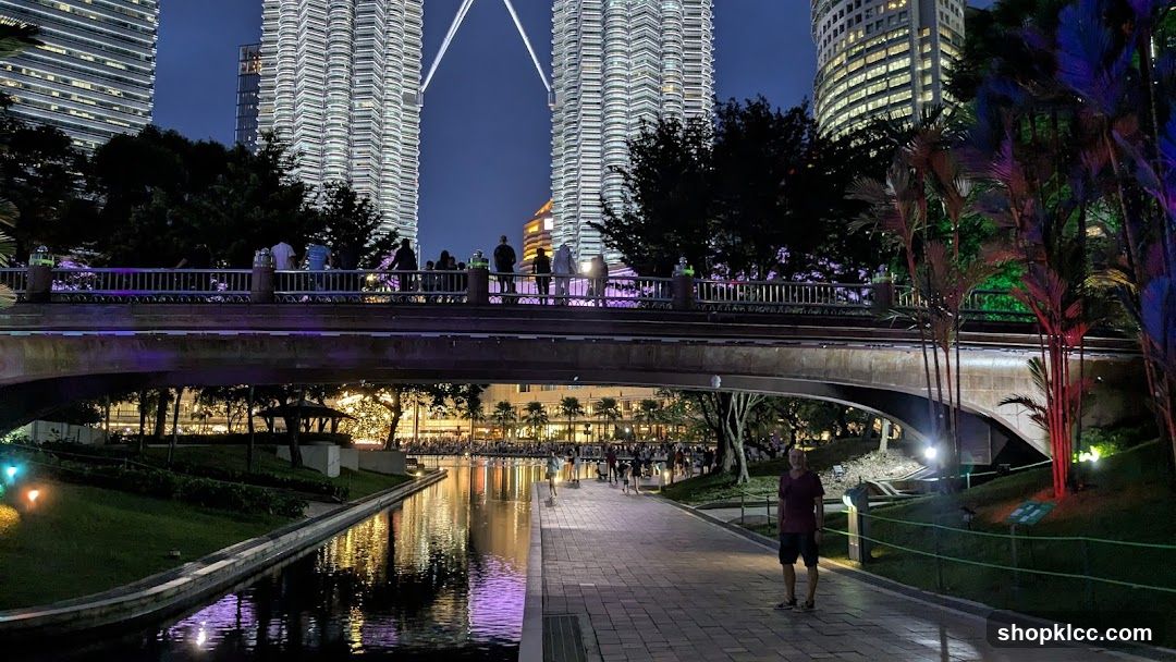 Night view of a park with illuminated buildings and a bridge