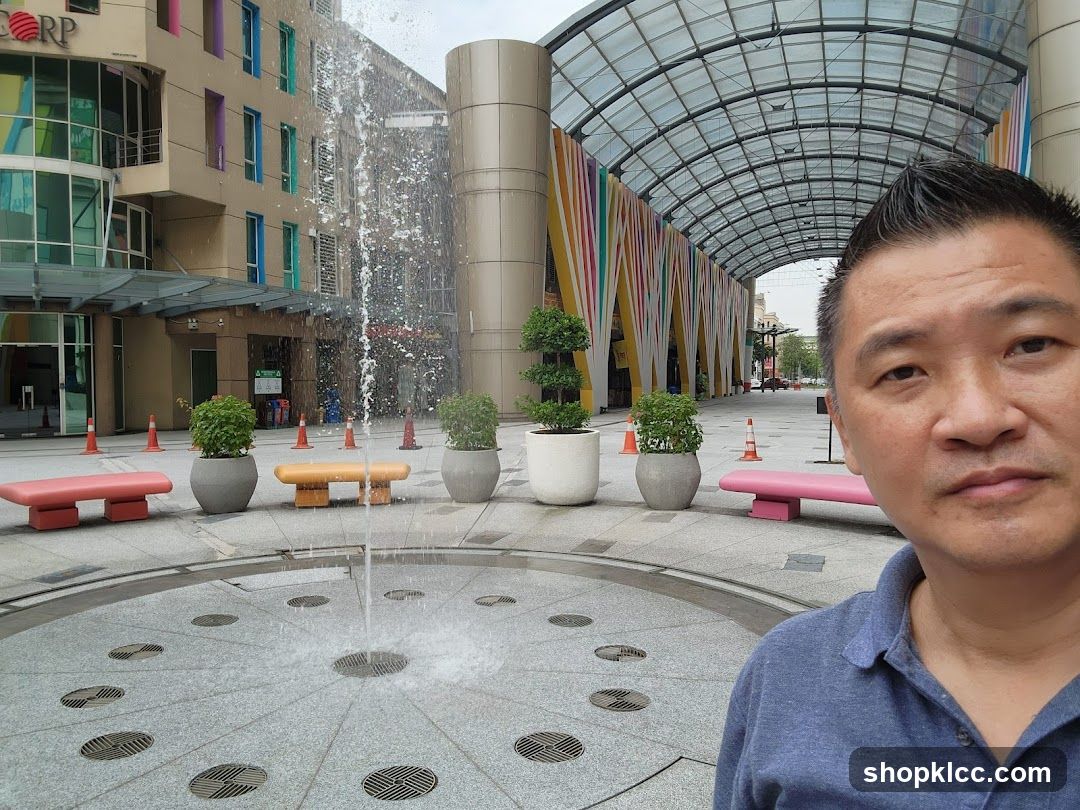 Outdoor plaza with fountain and person selfie