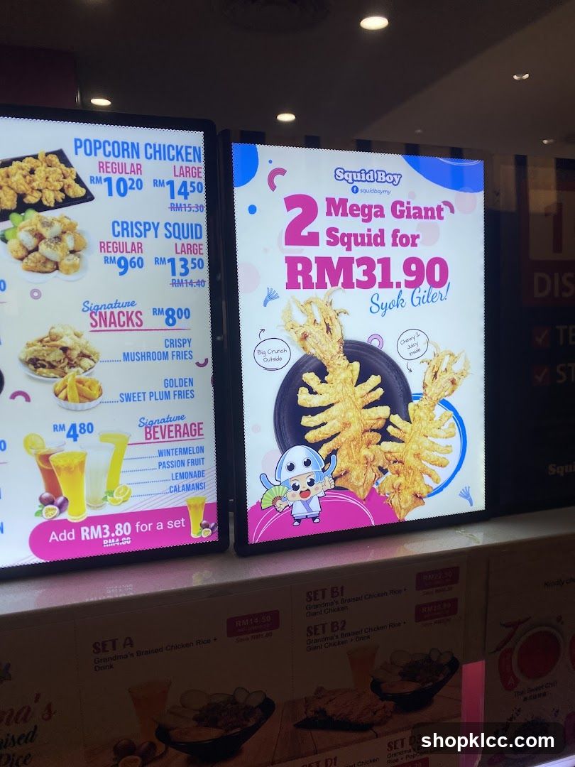 Digital menu display showing food items and prices, including popcorn chicken, crispy squid, signature snacks, beverages, and a special offer for two giant squid.