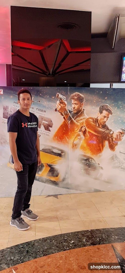 Man Poses in Front of Movie Poster