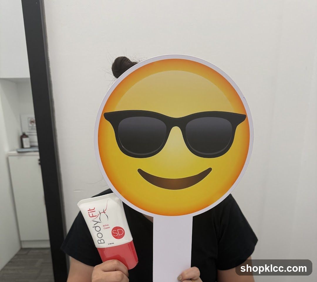 Person holding a BodyFit cream and a smiley face prop