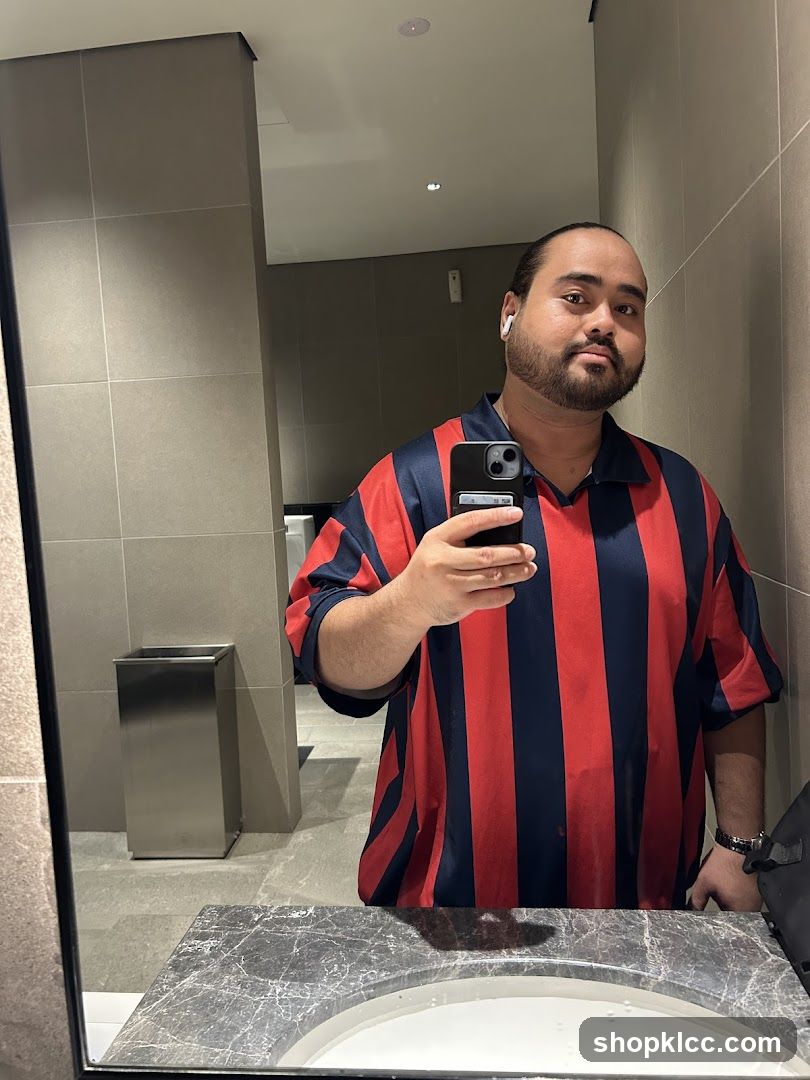Man in striped shirt taking a mirror selfie
