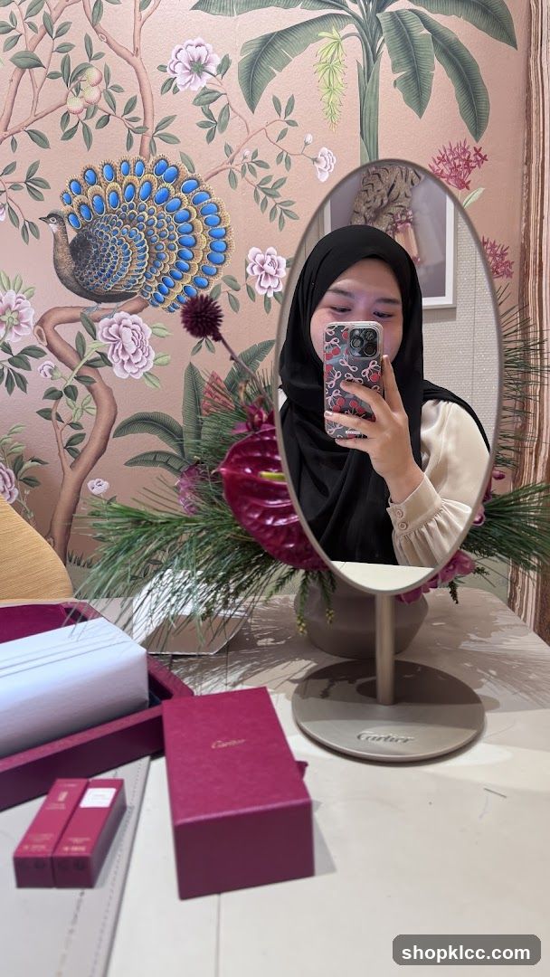 Woman taking a mirror selfie with Cartier boxes