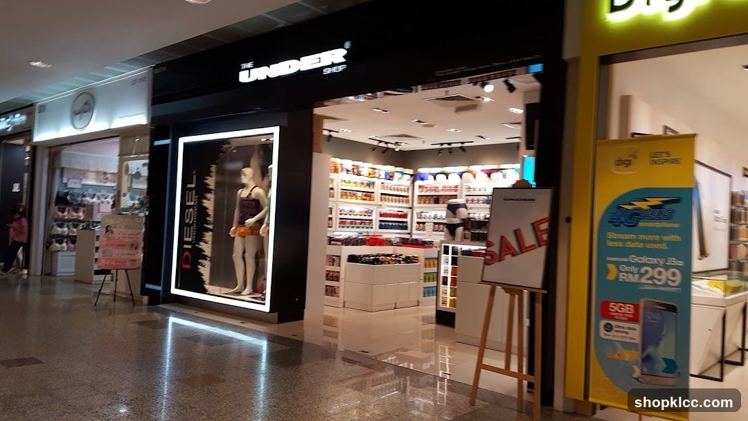 The exterior of a retail store called "The Under Shop" is visible, with a mannequin in a display window. Inside, shelves are stocked with various items. A sign on an easel reads "SALE". To the right, a yellow banner advertises a mobile phone plan.