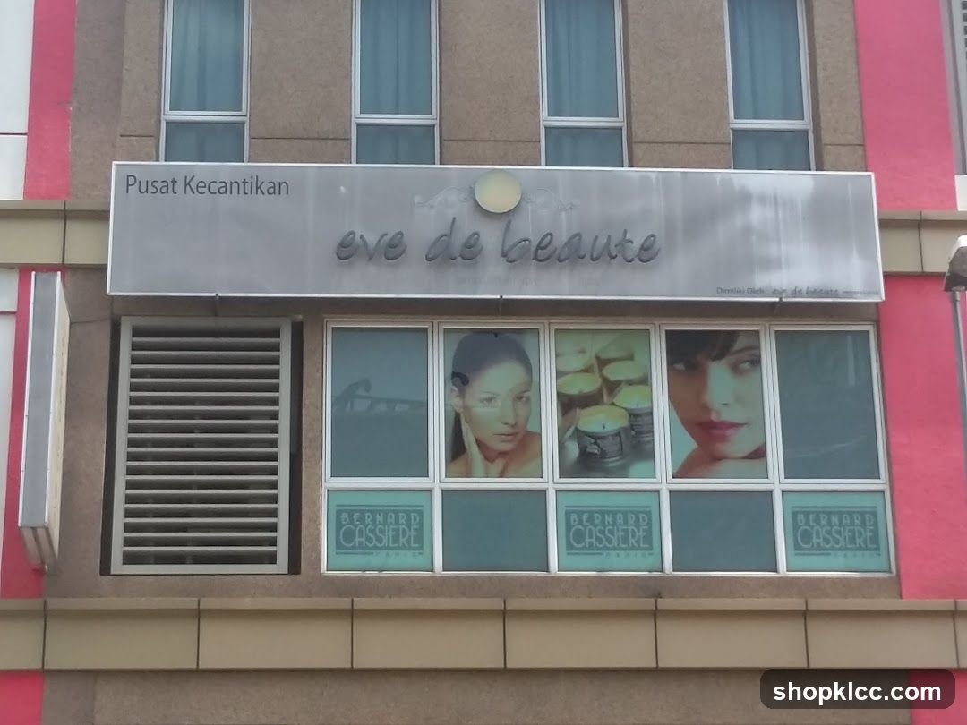 The exterior of a beauty salon with a large sign that reads "Pusat Kecantikan eve de beaute". Below the sign are several windows displaying images of women and products. The lower windows have "BERNARD CASSIERE PARIS" branding.