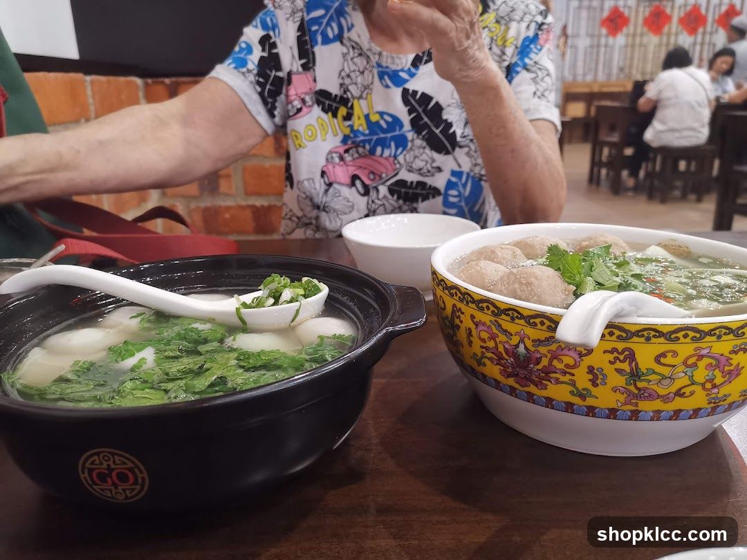 Two bowls of soup with meatballs and dumplings