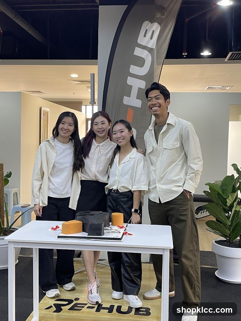 Four people posing behind a table with a cake