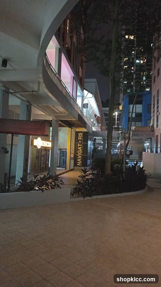 Night scene of a commercial area with illuminated storefronts and signage.