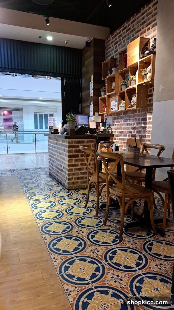 Interior of a cafe with brick walls and patterned floor tiles.