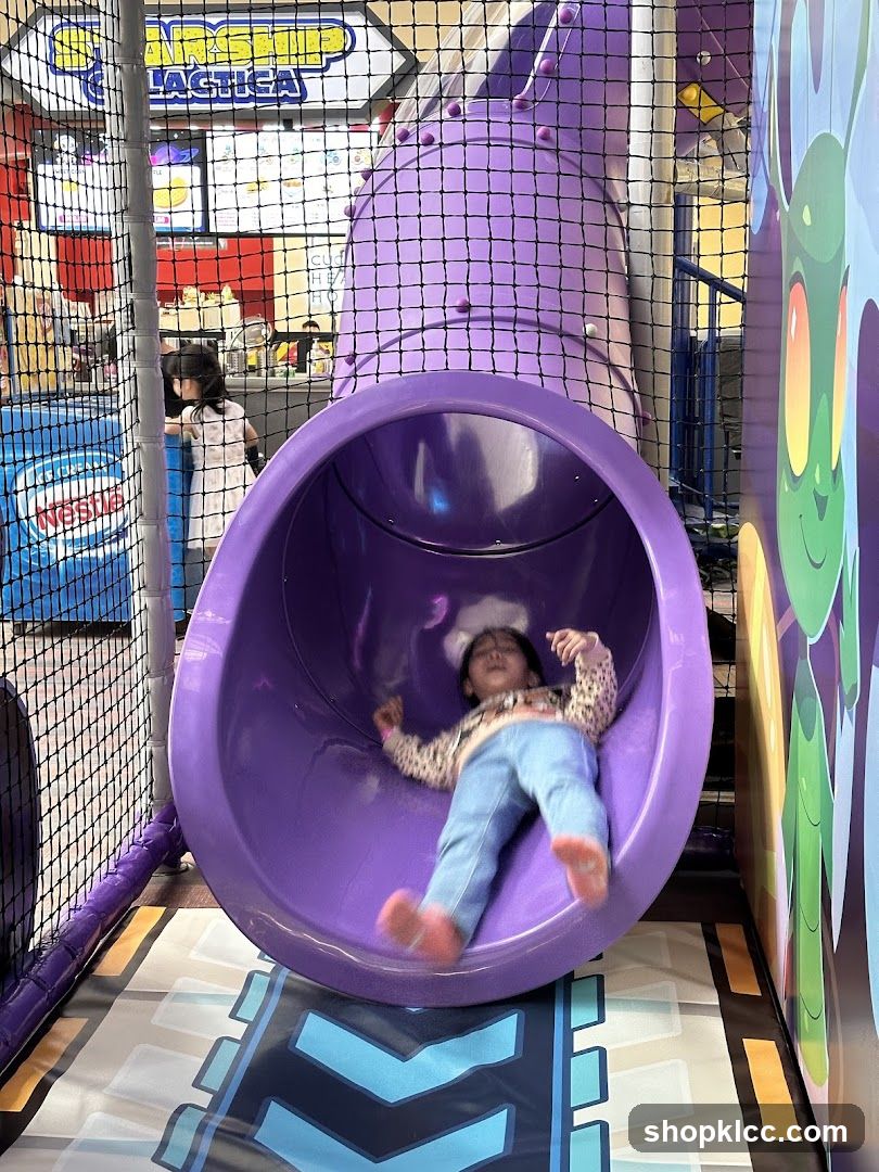Child sliding in purple tube at indoor play area