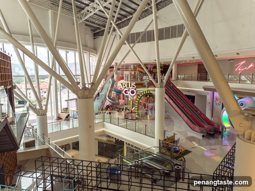 Interior of a multi-level shopping mall with escalators and an entertainment area.