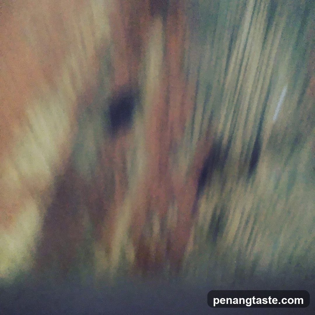 The image is an abstract, blurry depiction of vertical lines in shades of brown, green, and yellow. The lines are blurred and appear to be in motion, creating a sense of movement or a streaky effect. There are darker patches within the lighter areas, adding some contrast. The overall impression is of a textured, abstract pattern.