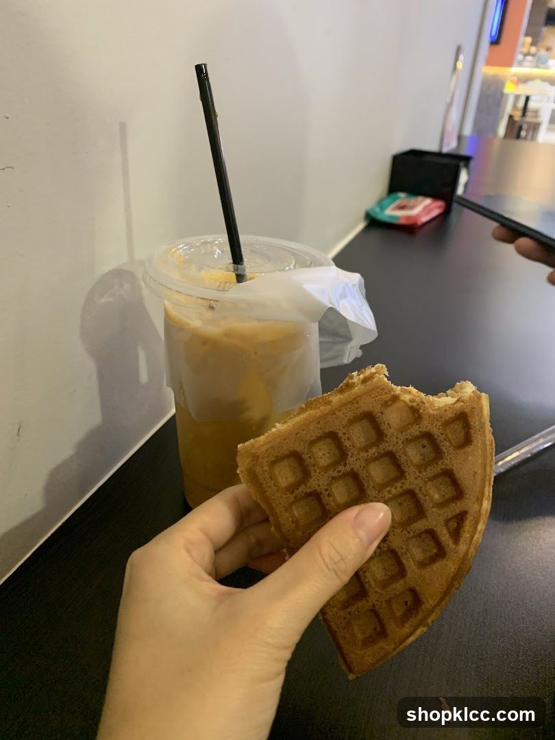 Hand holding a waffle with a coffee drink