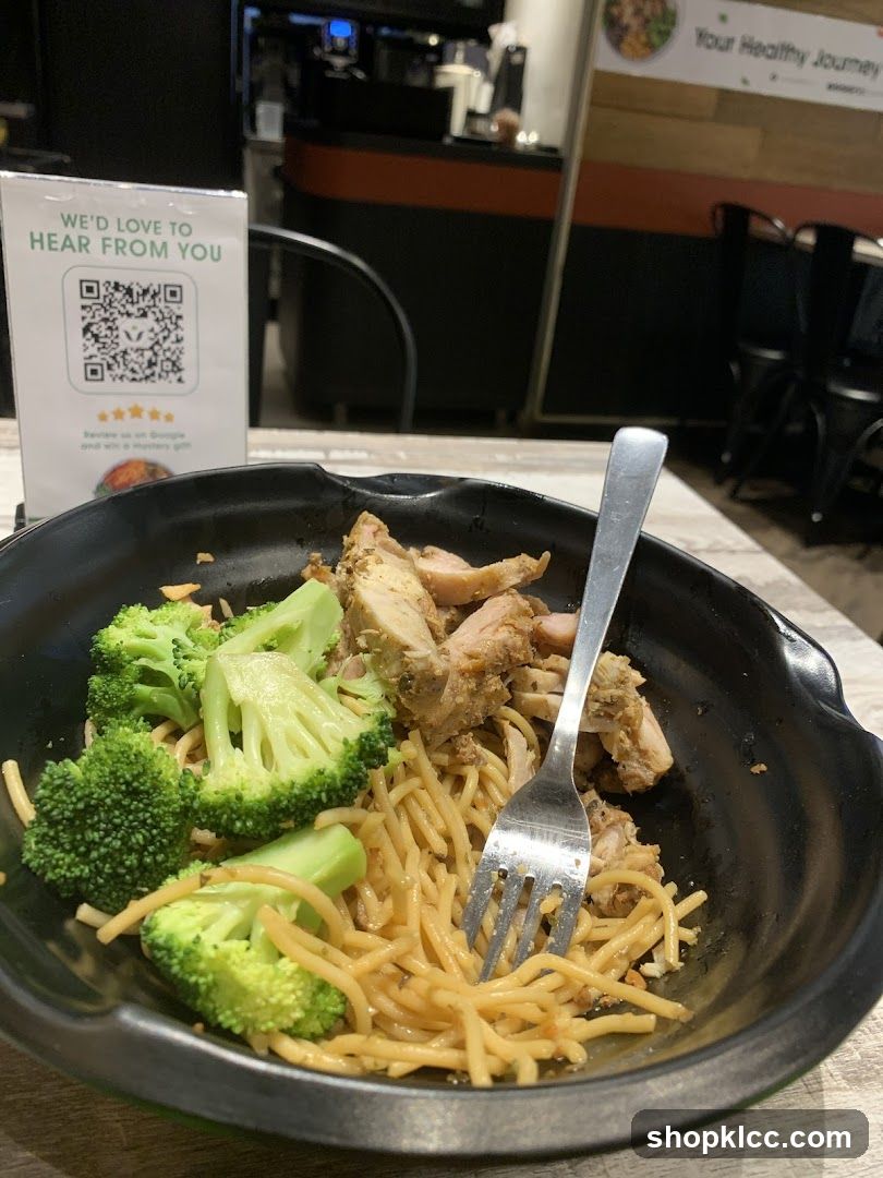 Noodle dish with broccoli and chicken in a black bowl