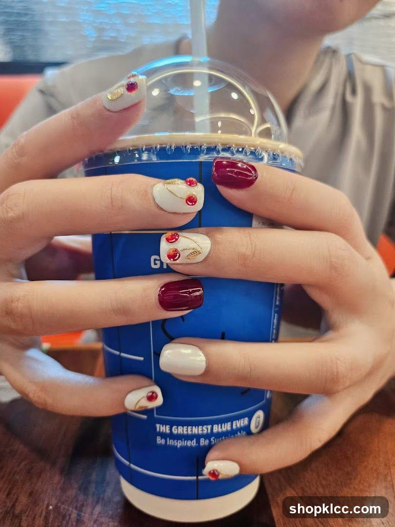 Hands holding a blue cup with cherry-themed nails