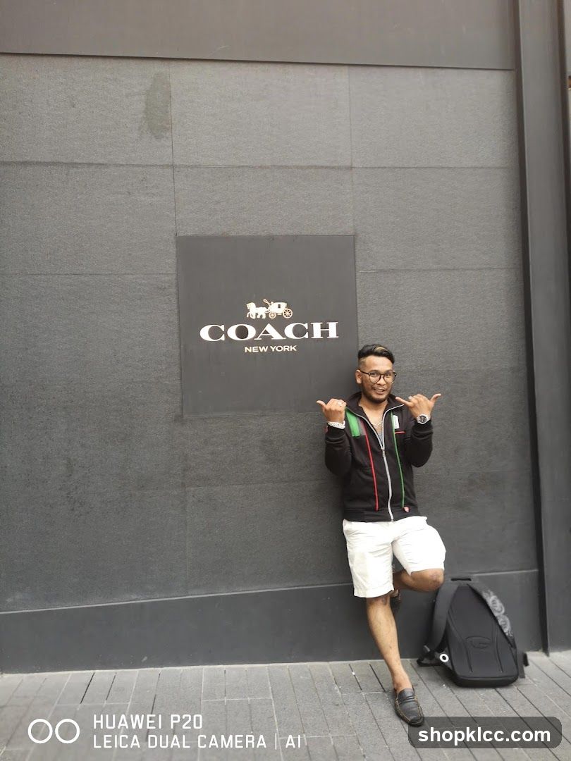 Man posing in front of Coach New York logo