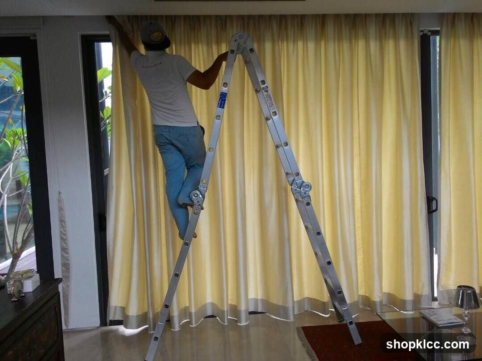 Man on Ladder Adjusting Curtains