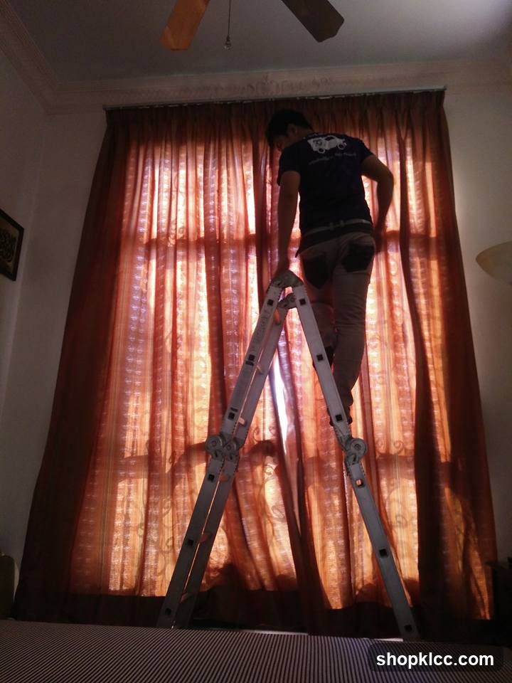 Man on Ladder Adjusting Curtains