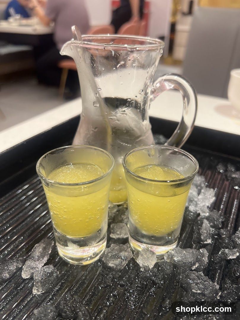 Two shots of yellow liquid with a pitcher