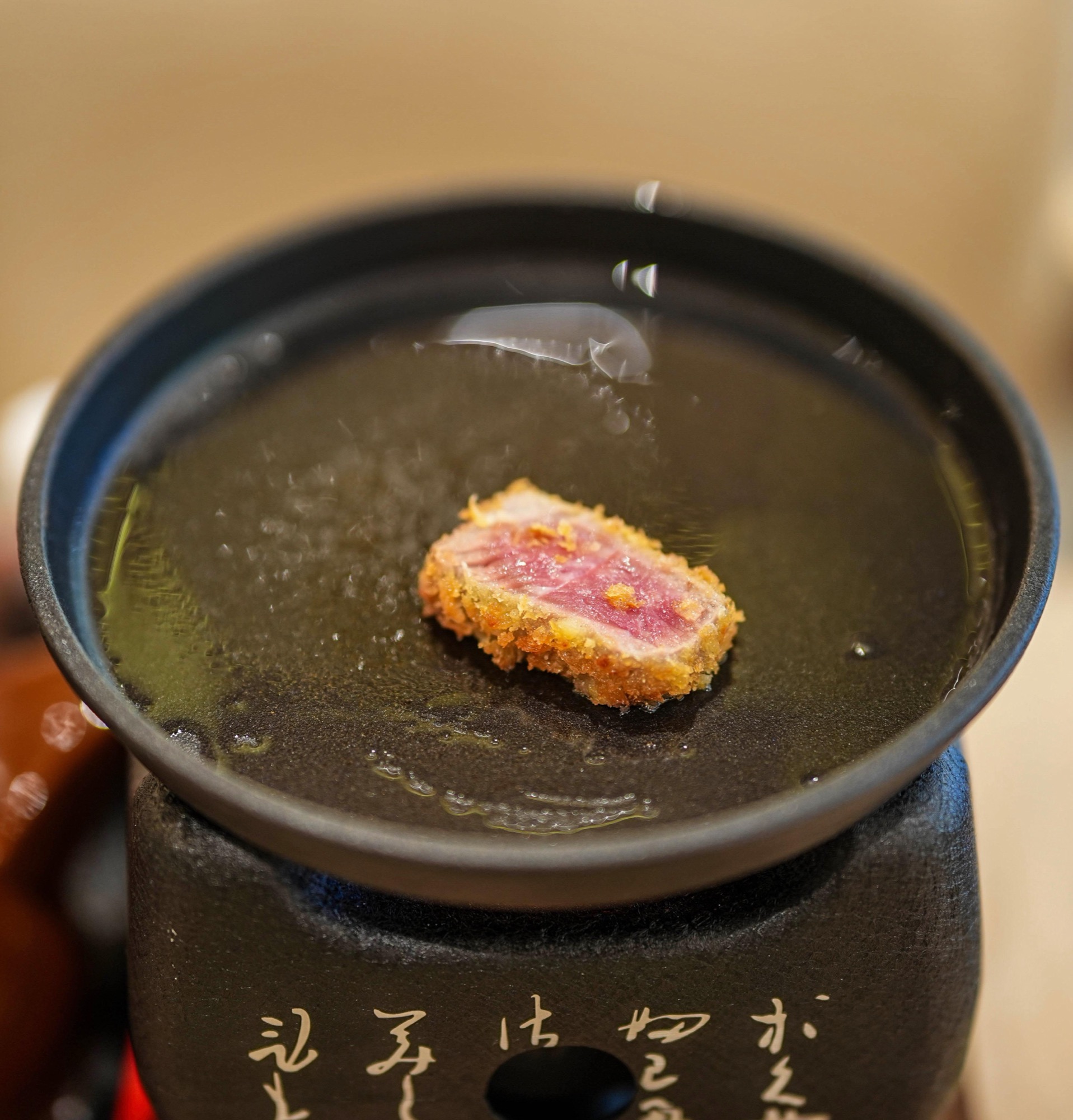A slice of rare gyukatsu finishing on the tabletop hot plate at Kyoto Katsu Suria KLCC